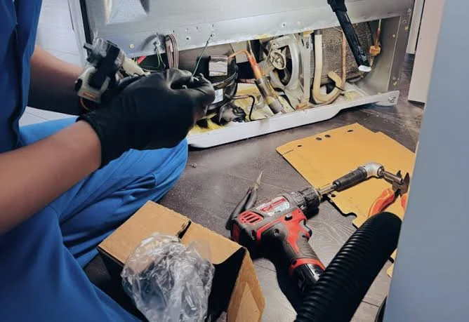 Close-up of an appliance repair with tools and exposed components