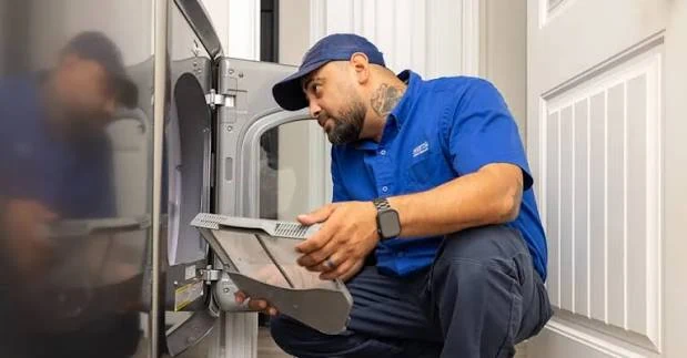 Technician inspecting a clothes dryer door and drum